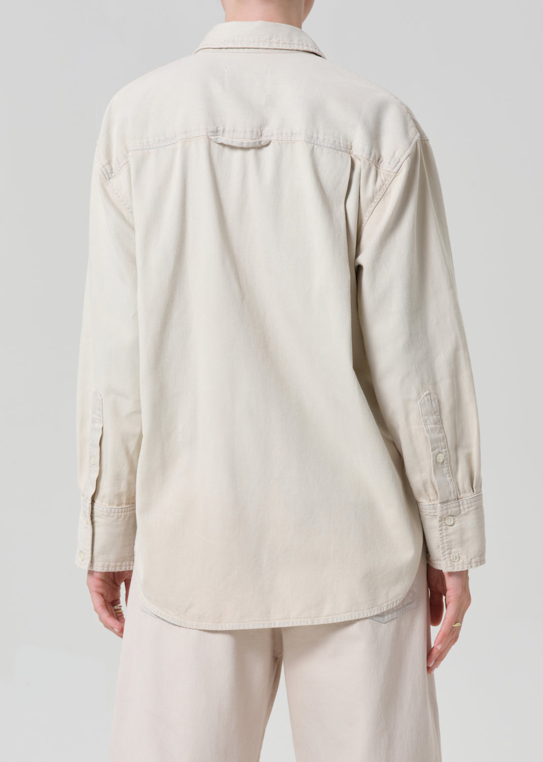 Person wearing a beige shirt and pants on a plain background