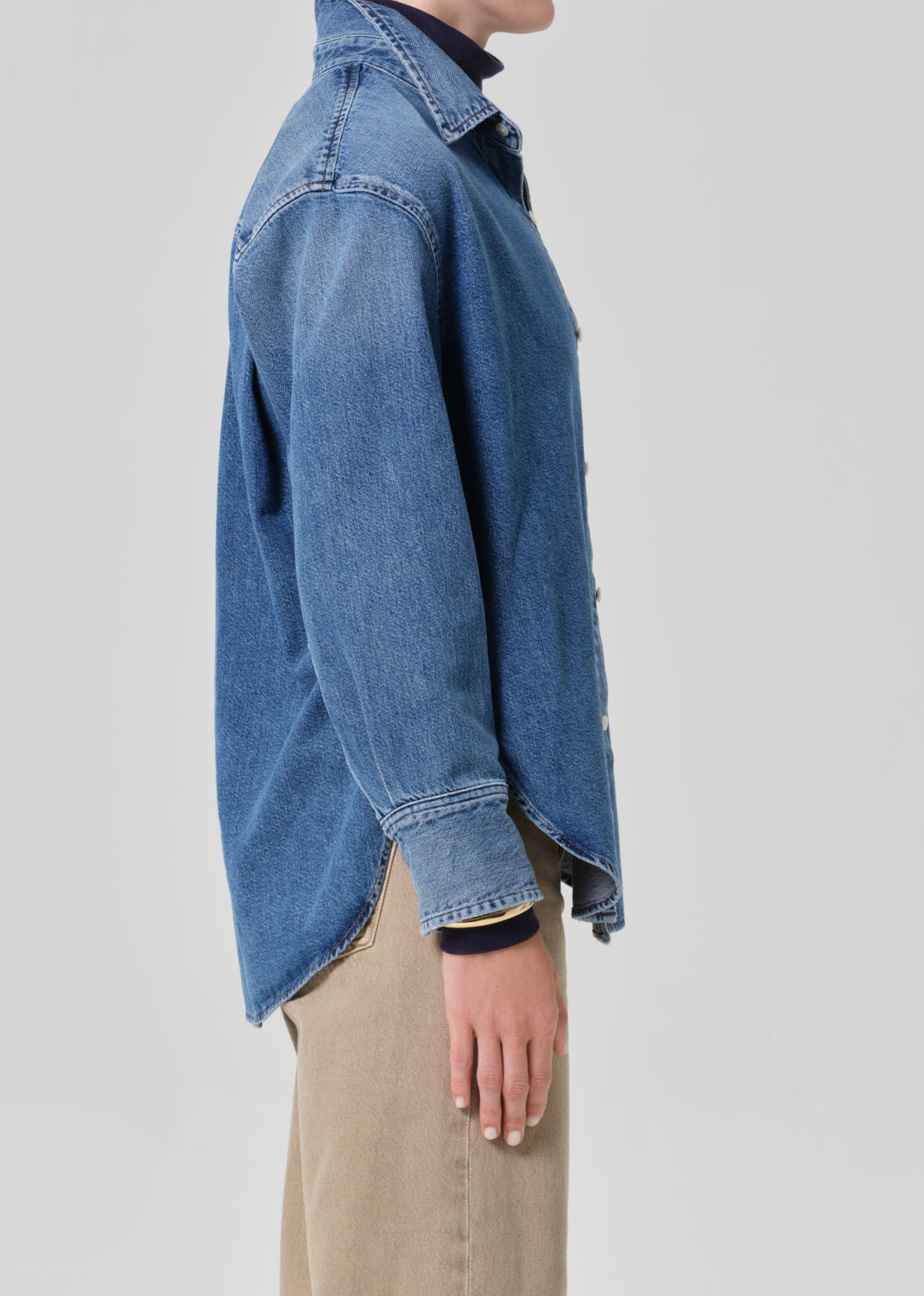 Person wearing a blue denim jacket on a plain background
