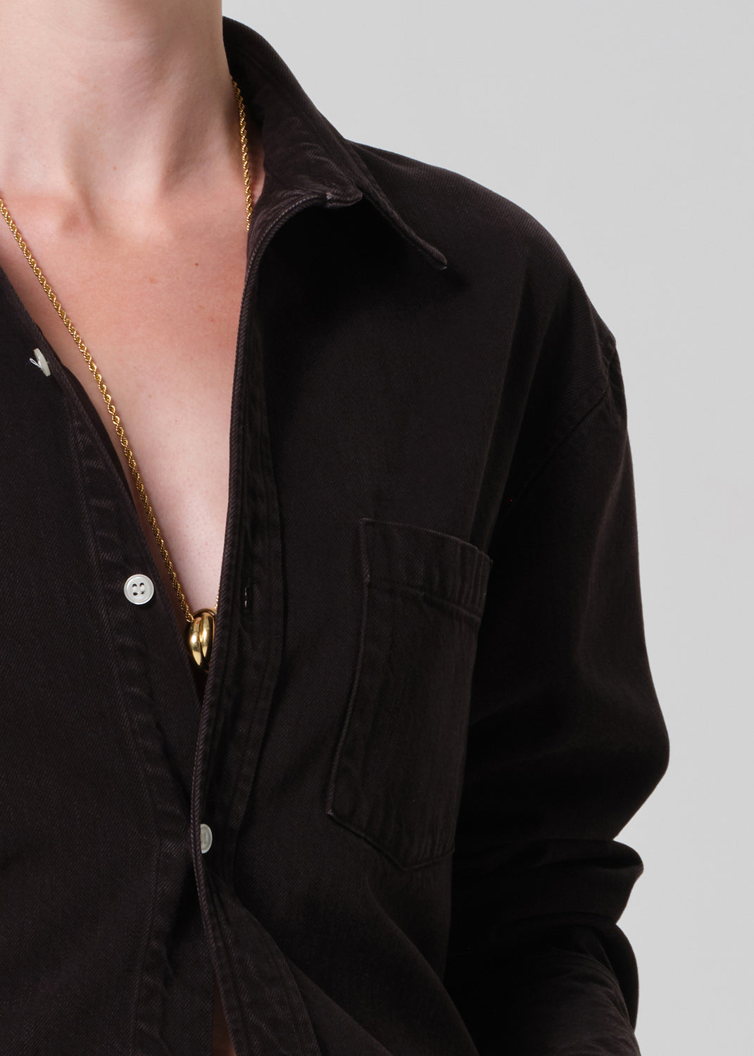 Person wearing a brown  button-up shirt and brown pants on a plain background