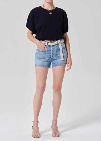 Person wearing a navy t-shirt and denim shorts on a plain background