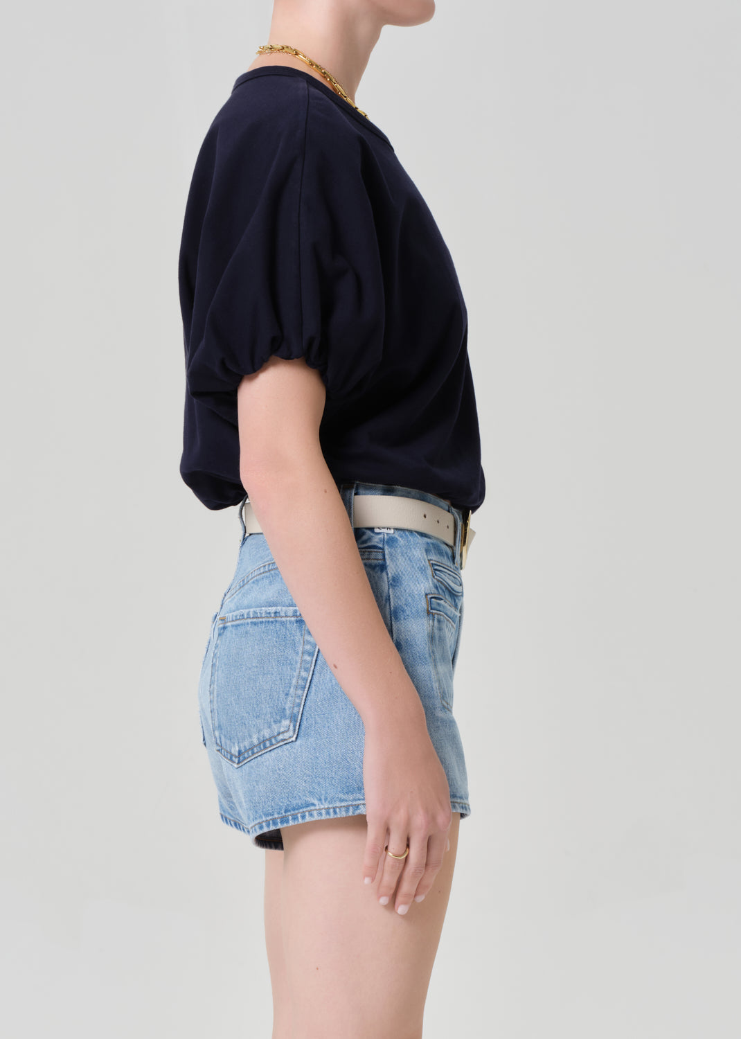Person wearing a navy top and denim skirt on a light gray background