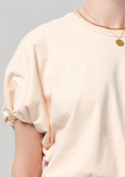 Person wearing a light coral top on a gray background