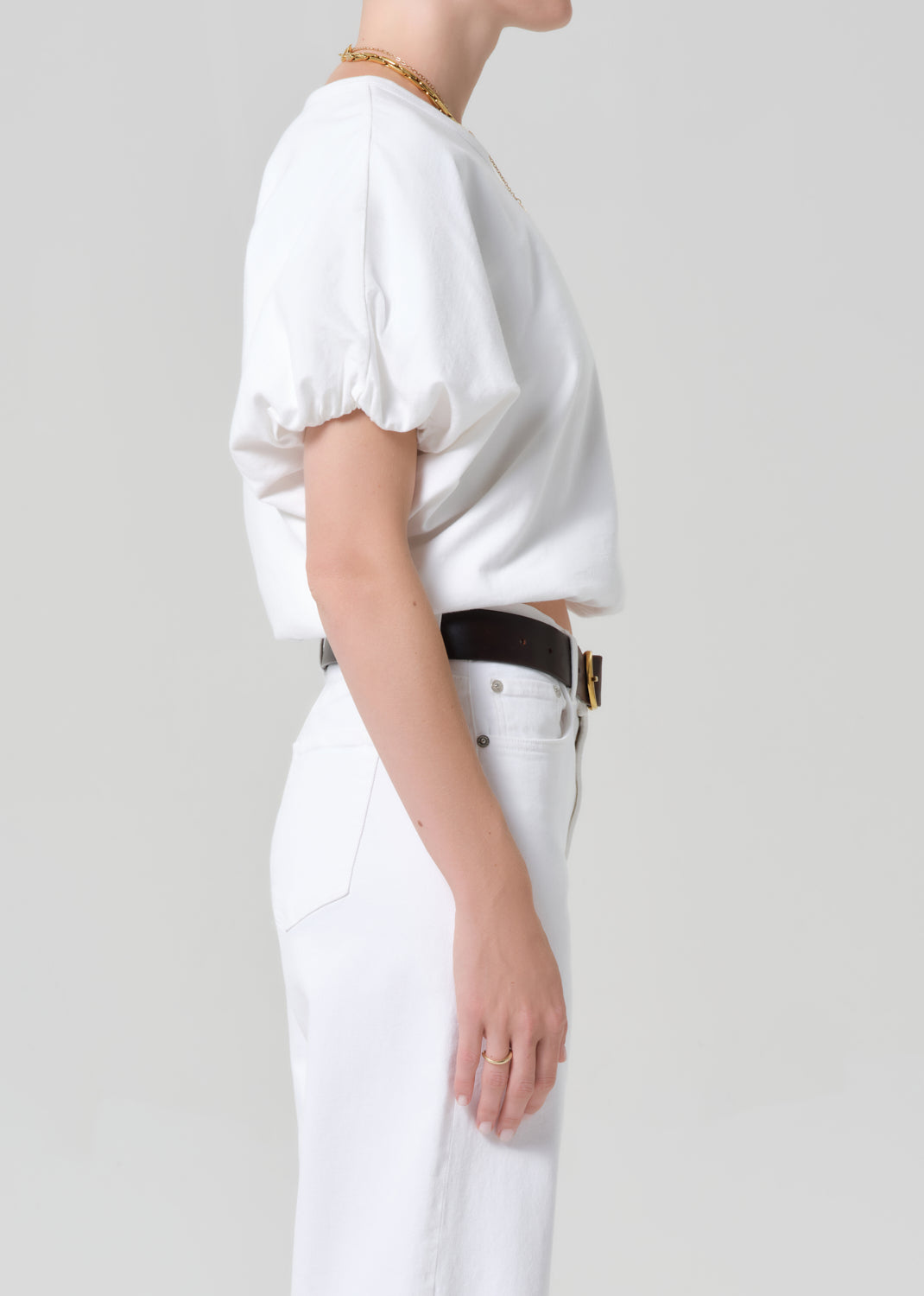 Person wearing a white outfit with a belt on a plain background