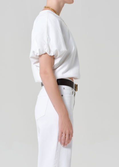 Person wearing a white outfit with a belt on a plain background