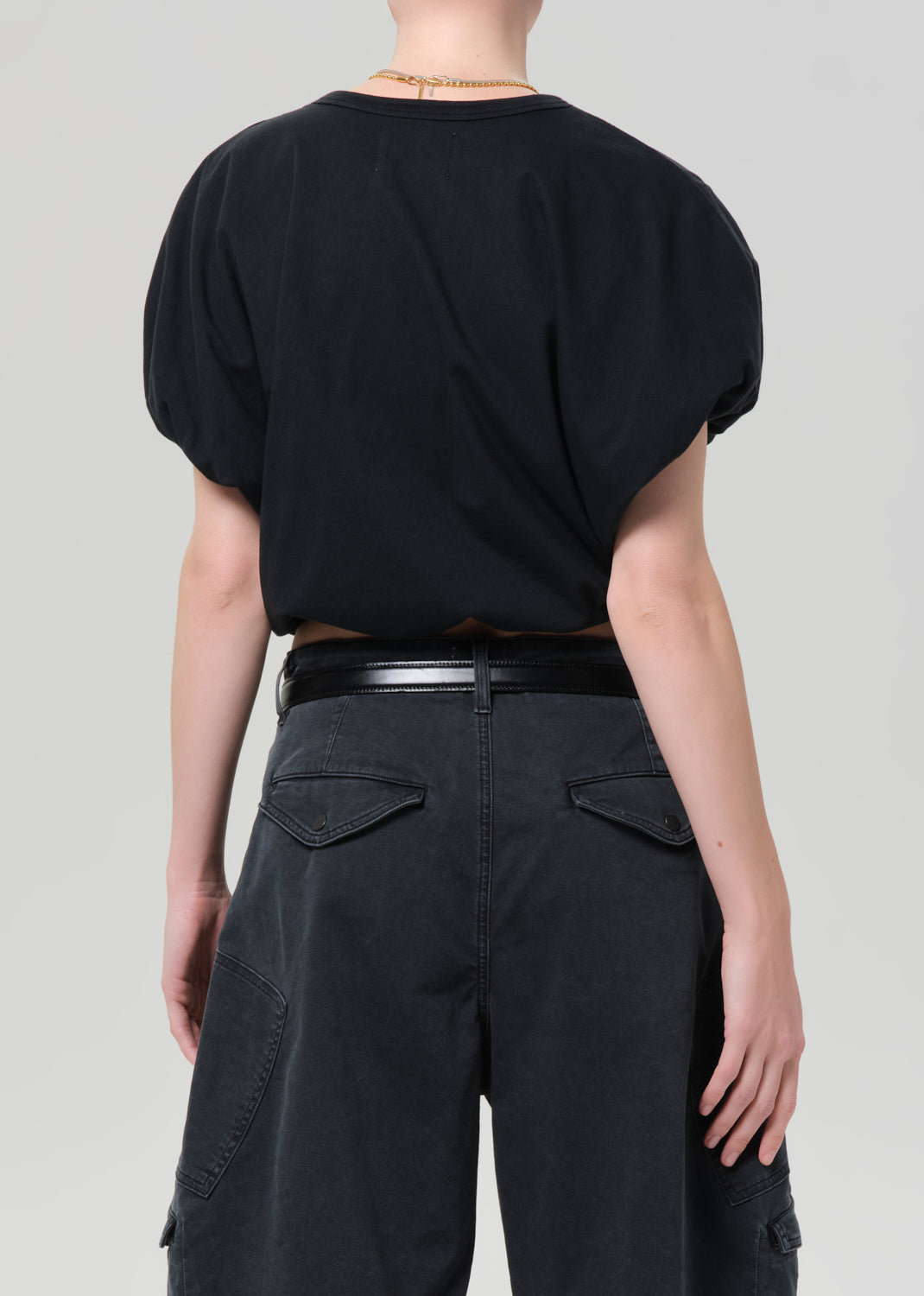 Person wearing a black top and black pants on a light gray background