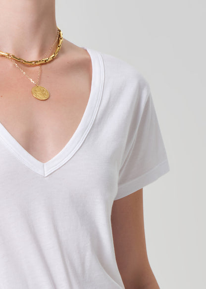 White t-shirt worn by a person with a gold necklace on a plain background