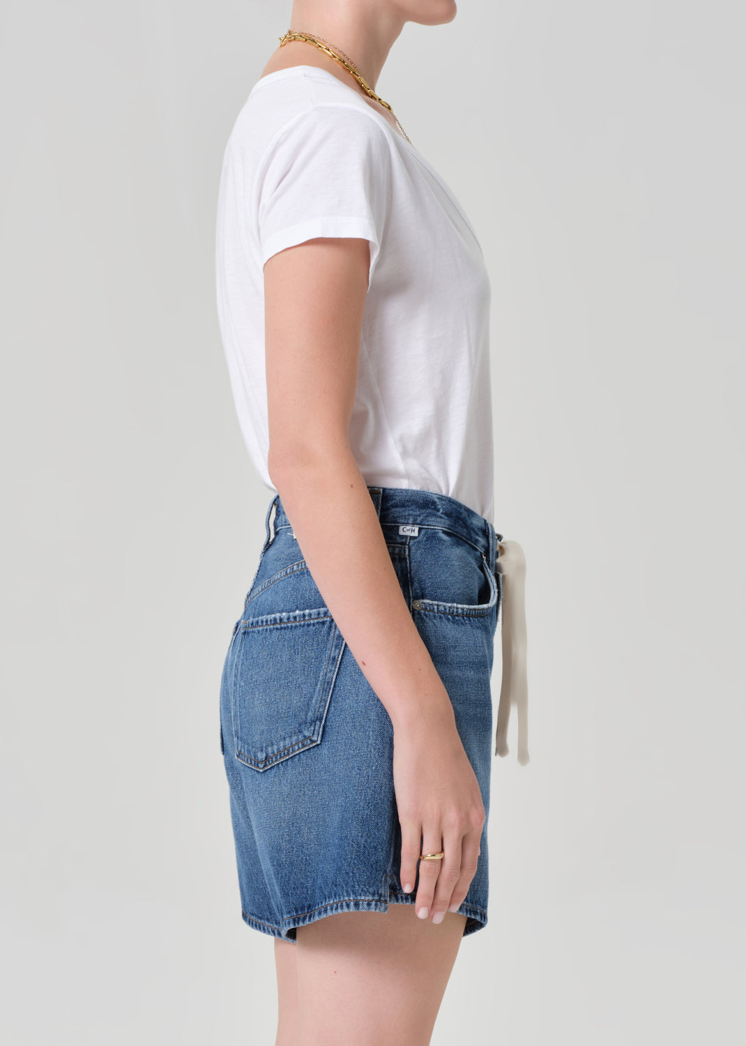 Person wearing a white t-shirt and blue denim skirt on a plain background