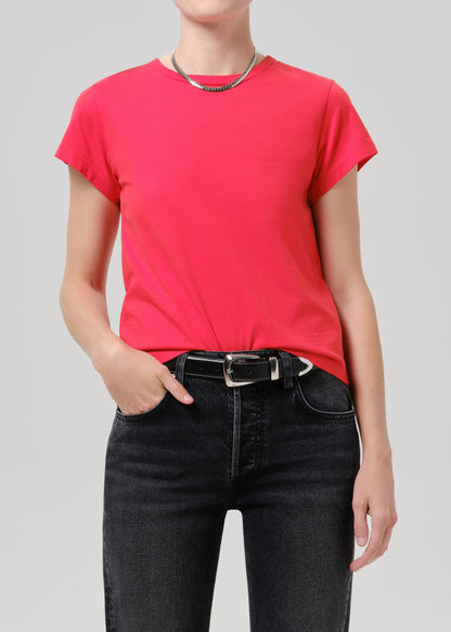 Person wearing red t-shirt with dark pants on a grey background