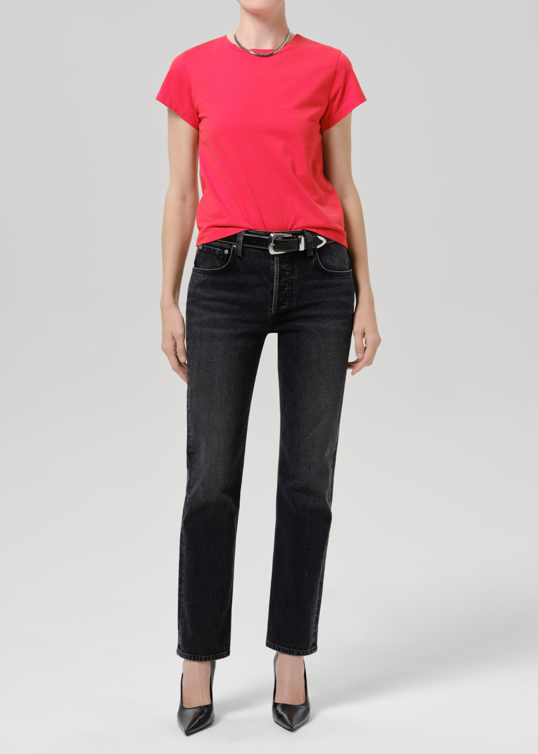 Person wearing red t-shirt with dark pants on a grey background