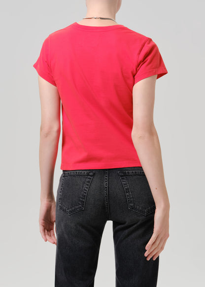 Person wearing red t-shirt with dark pants on a grey background