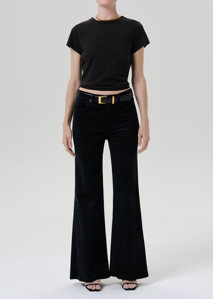 Person wearing a black short sleeve crewneck tee with black wide leg jeans and black sandals on a grey background