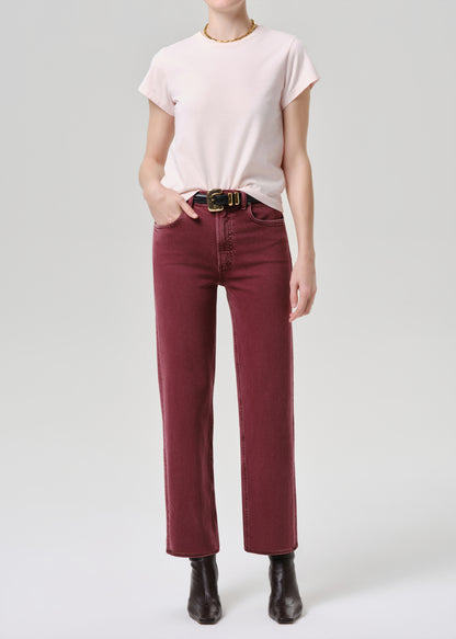 Person wearing a light pink t-shirt, maroon pants, and black boots on a grey background
