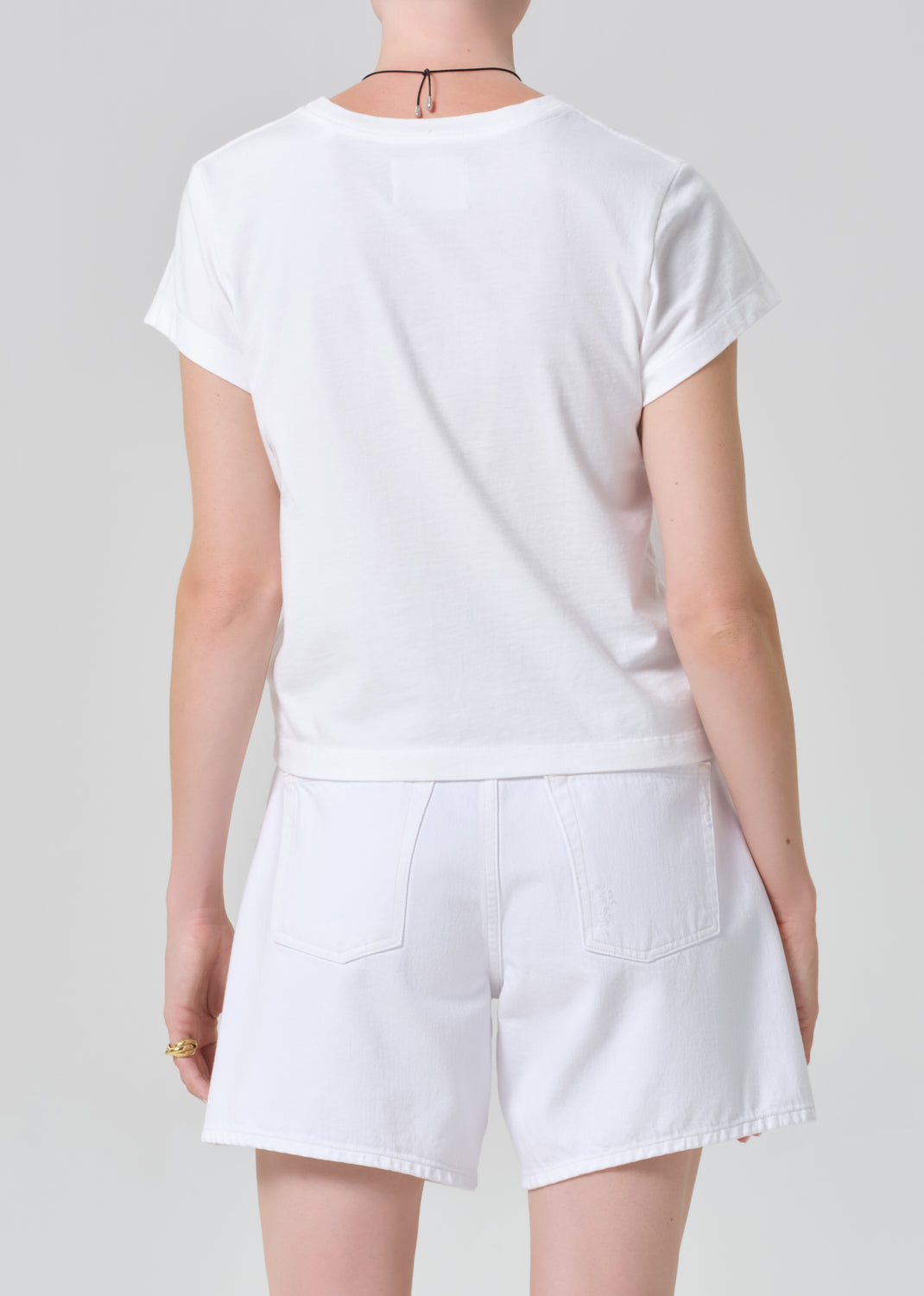 Person wearing a white t-shirt and shorts on a plain background