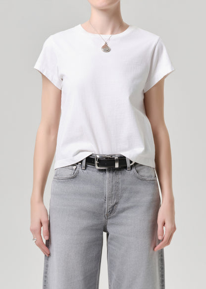 Person wearing a white t-shirt and grey jeans on a grey background.
