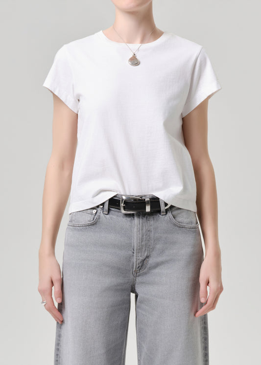 Person wearing a white t-shirt and grey jeans on a grey background.