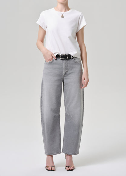 Person wearing a white t-shirt and gray wide-leg jeans on a grey background.