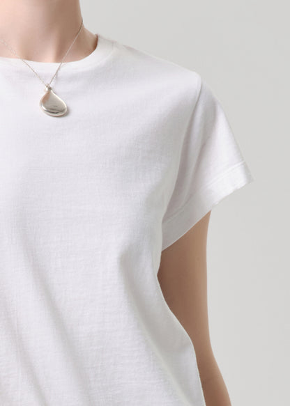 White t-shirt worn with a necklace on a grey background.