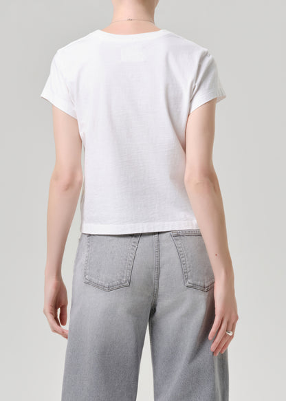 Person wearing a white t-shirt and grey jeans on a grey background.