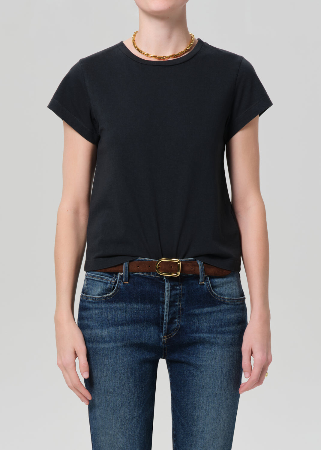 Person wearing washed black tee with blue jeans