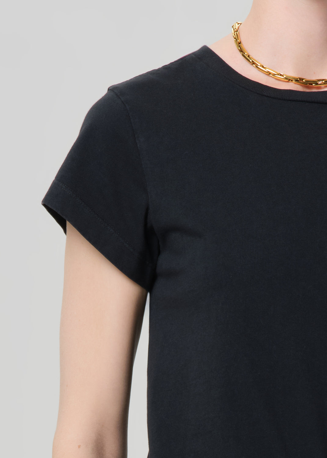 Person wearing washed black tee with blue jeans