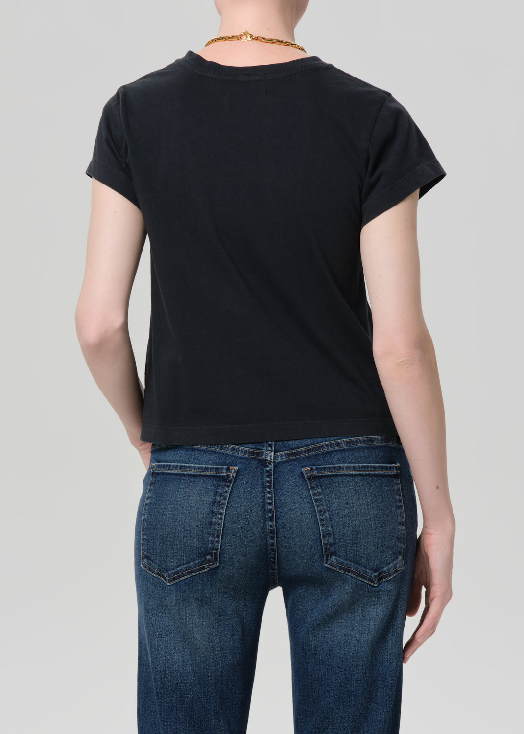 Person wearing washed black tee with blue jeans