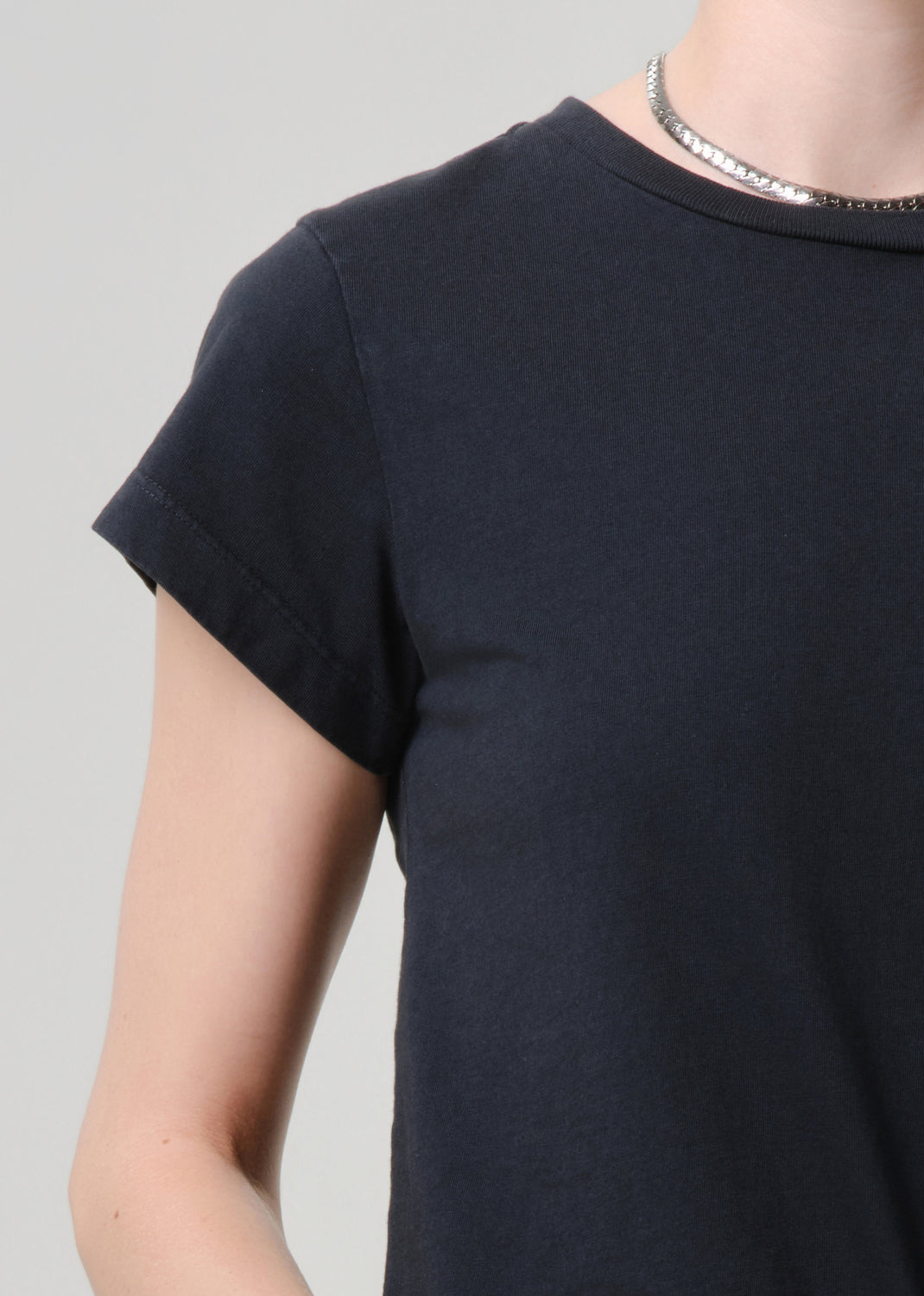 Person wearing a plain black t-shirt against a grey background.