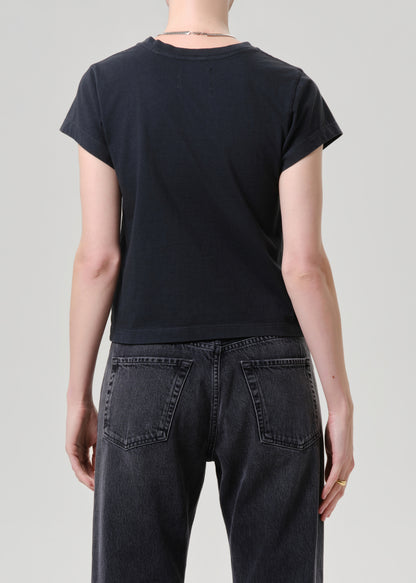Person wearing a black t-shirt and dark jeans on a grey background.