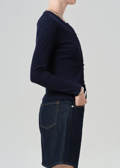 Person wearing a navy blue cardigan over dark denim shorts on a plain background