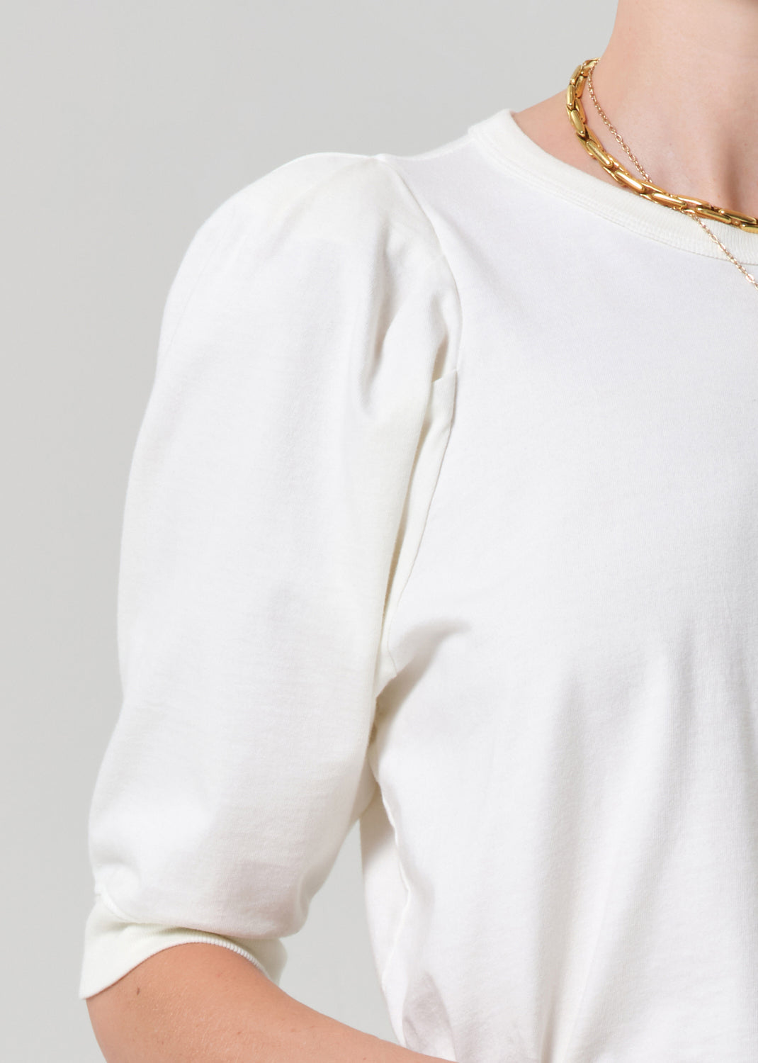 White blouse with gold trim on a plain background