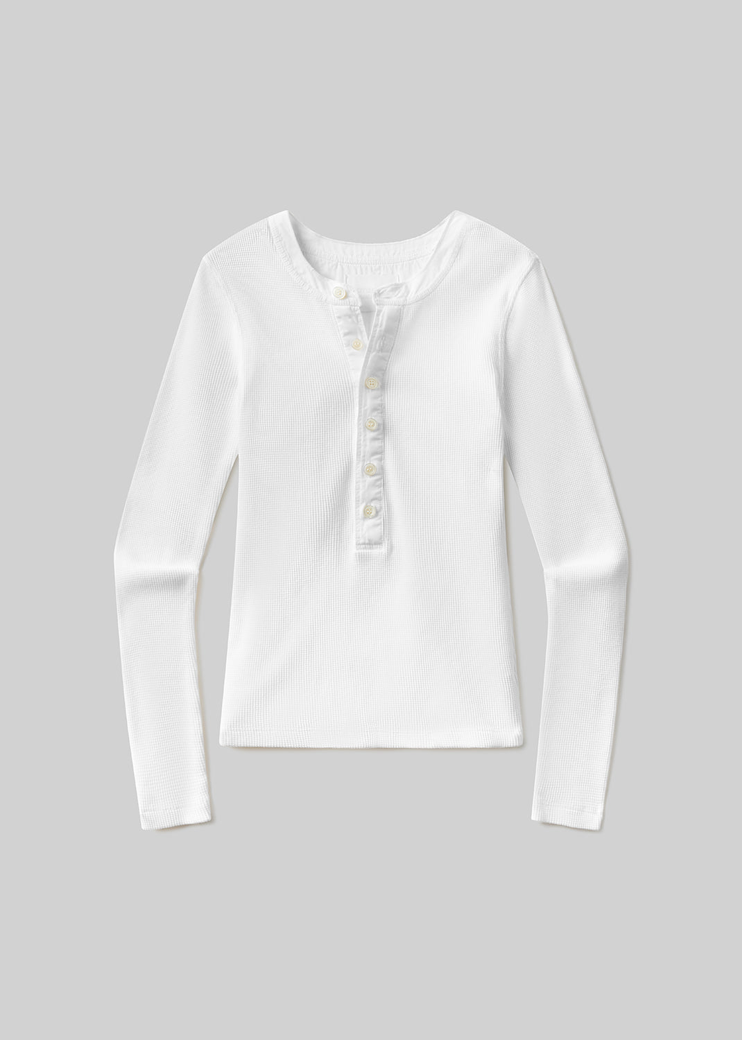 White waffle-knit long-sleeve Henley top with a round neckline, partial front button closure, fitted silhouette, and textured finish, front flat lay view on a grey background.