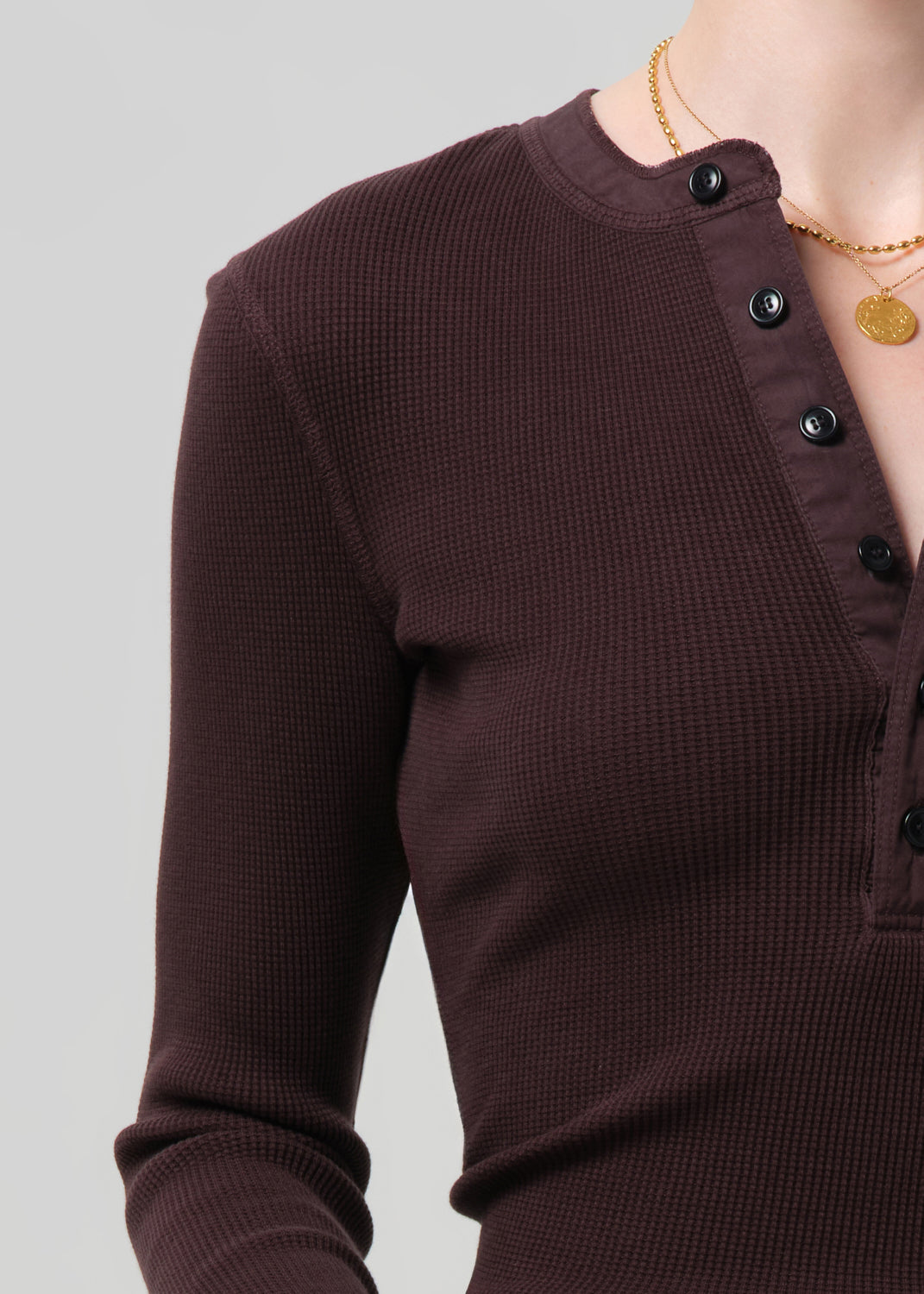 Brown ribbed sweater with black buttons on a gray background