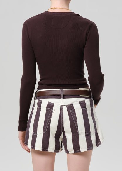Person wearing a brown long-sleeve top and striped shorts on a plain background