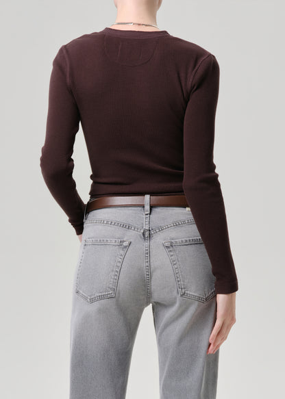 Rear view of a model wearing a dark brown long-sleeve crewneck top, a brown leather belt, and light grey jeans against a grey background.