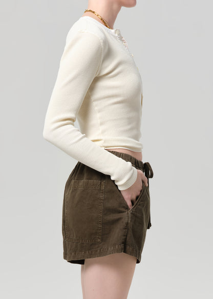 Person wearing a cream top and brown shorts on a plain background