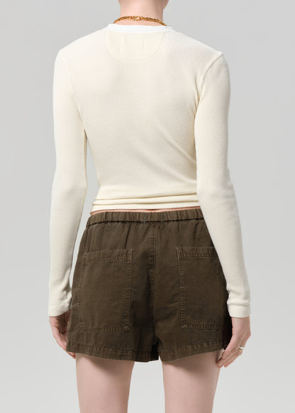 Person wearing a cream top and brown shorts on a gray background