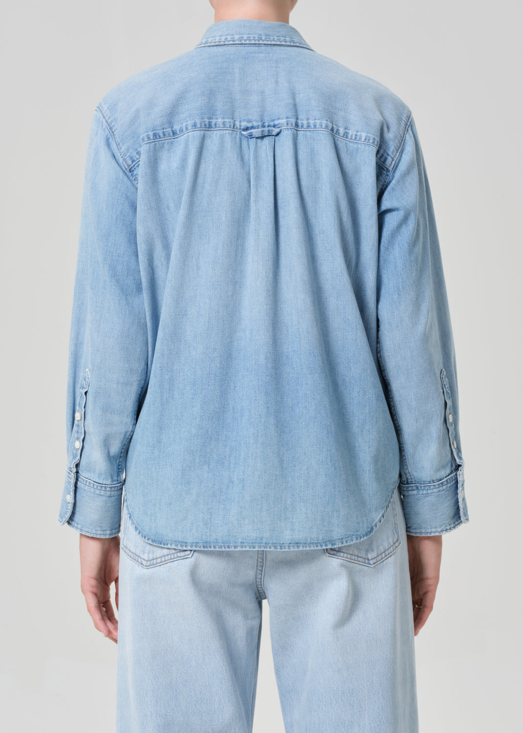 Light blue denim shirt worn by a person on a plain background