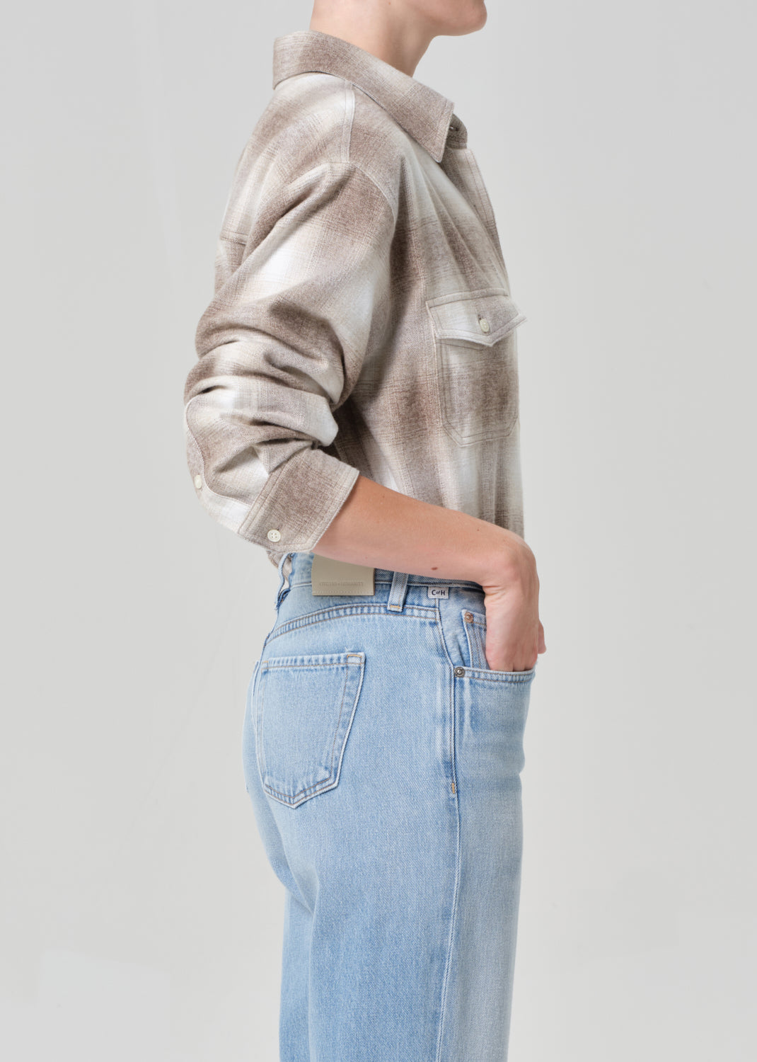 Person wearing a plaid shirt and light blue jeans on a plain background