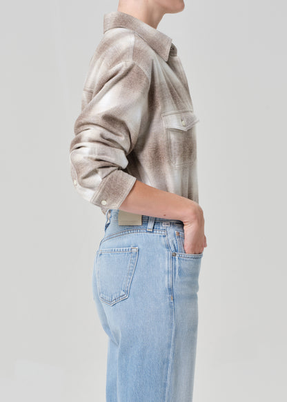 Person wearing a plaid shirt and light blue jeans on a plain background