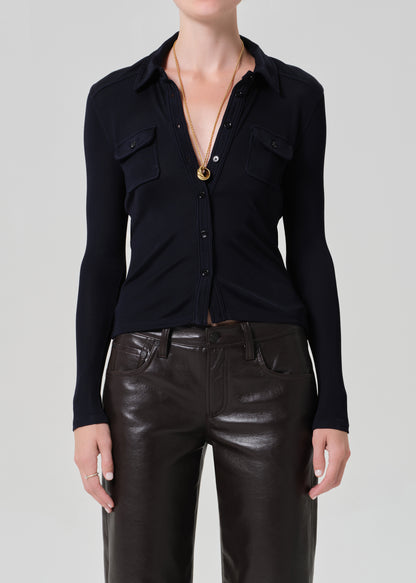 Person wearing a navy shirt and leather brown pants on a plain background