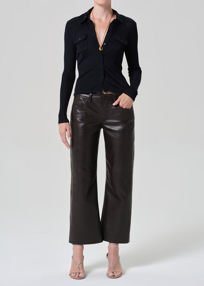 Person wearing a navy shirt and leather brown pants on a plain background