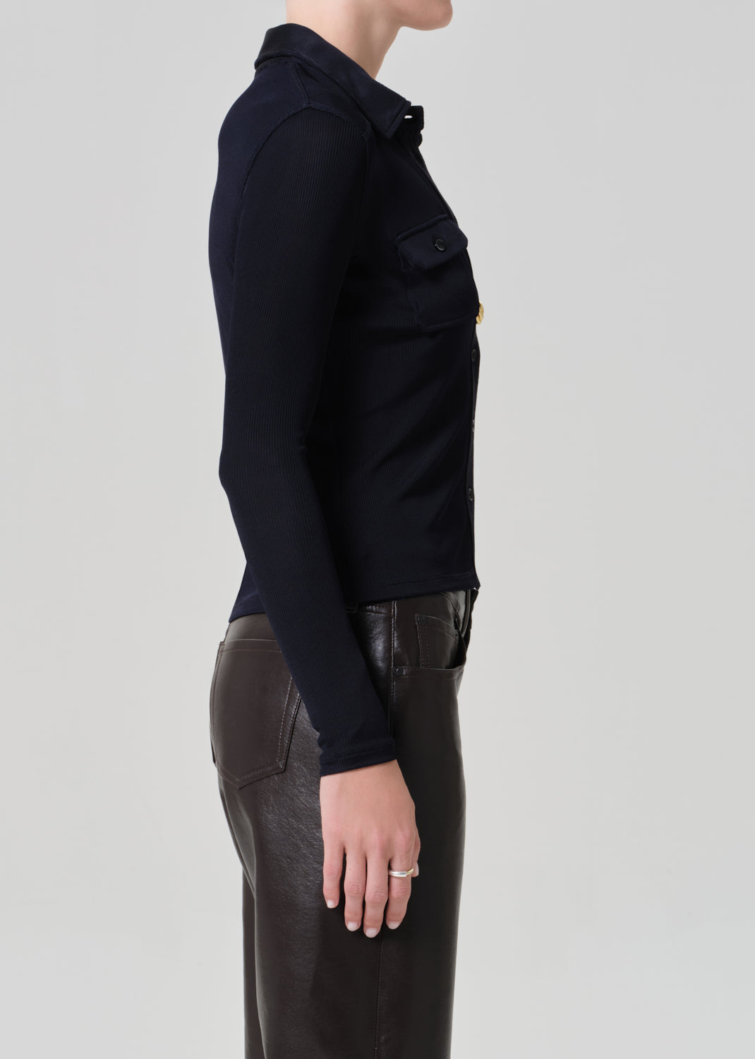 Person wearing a navy shirt and leather brown pants on a plain background