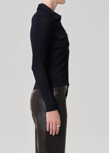 Person wearing a navy shirt and leather brown pants on a plain background