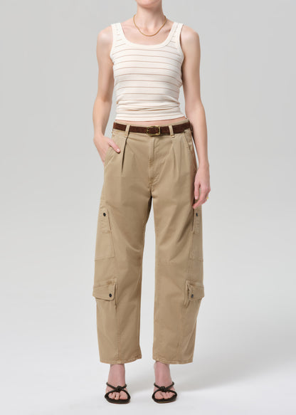 Person wearing a beige tank top and cargo pants on a grey background