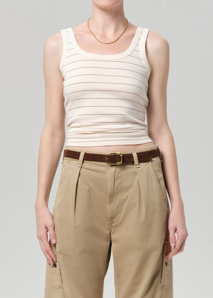 Person wearing a white striped tank top and beige pants with a brown belt on a gray background