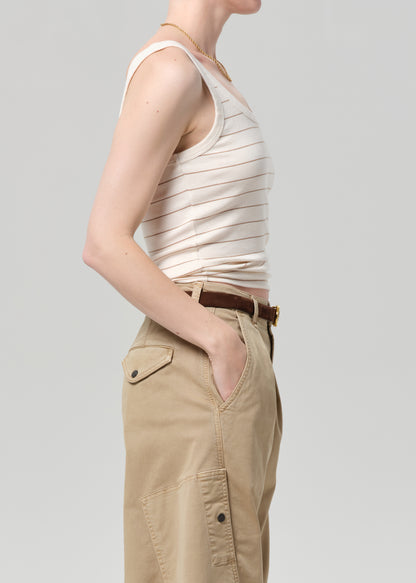 Person wearing a striped tank top and beige pants on a plain background