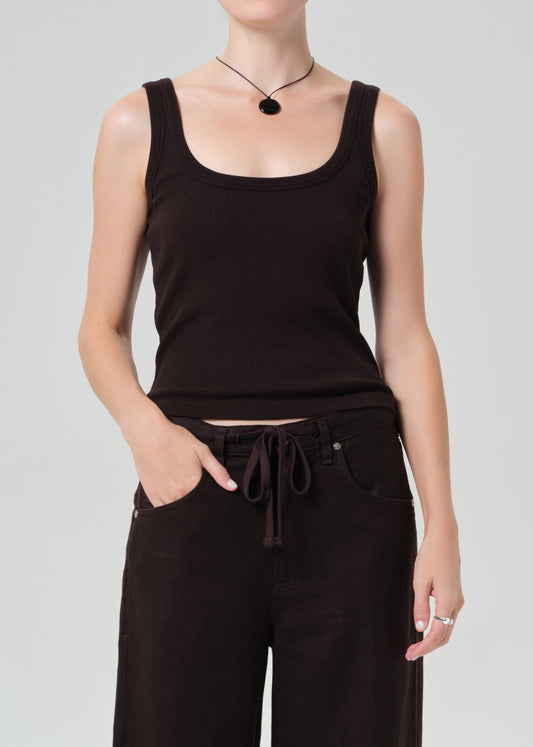 Person wearing a brown tank top and brown pants on a light gray background