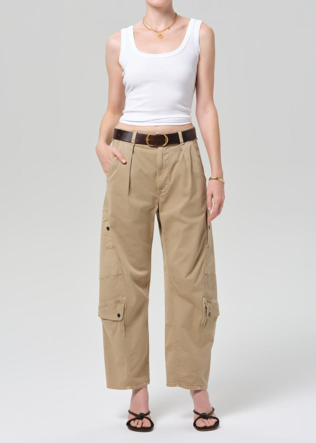 Person wearing a white tank top and beige cargo pants on a plain background