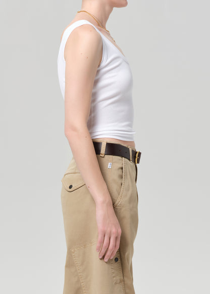 Person wearing a white tank top and beige pants on a plain background