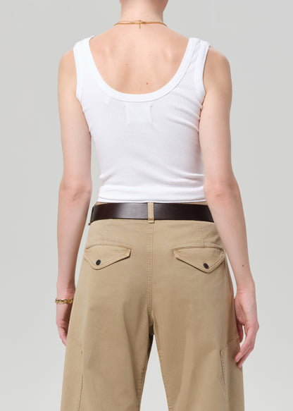 Person wearing a white tank top and beige pants on a plain background