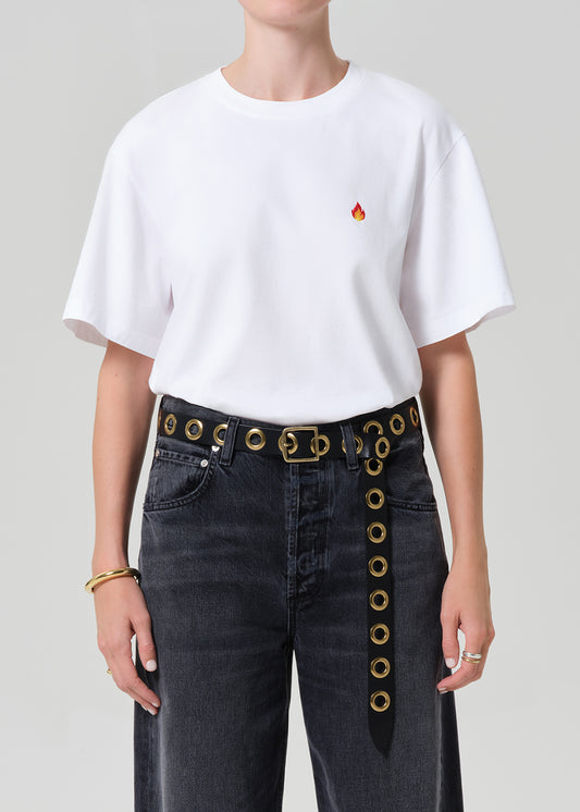 Person wearing a white t-shirt with a red logo and dark jeans on a plain background